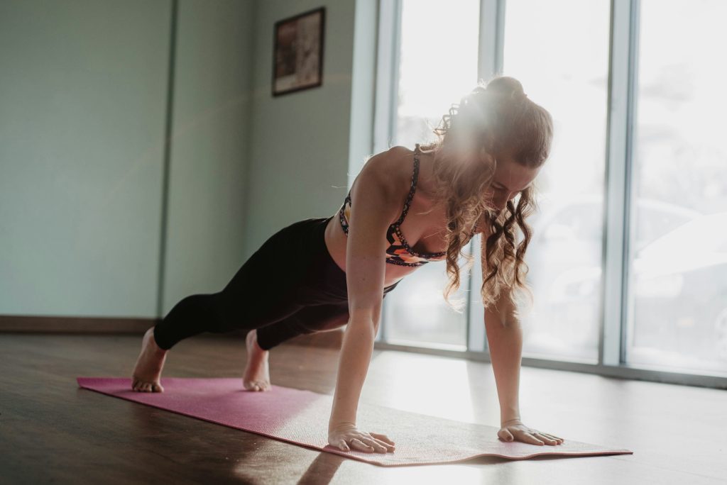 woman in black tank top and black leggings doing plank